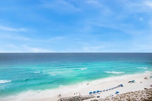 A beach with clear turquoise waters, a sandy shore, and a wooden walkway leading to the beach. - Shoreline Towers 1114 (Destin)