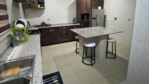 Une cuisine moderne dotée de plans de travail en granit, d’appareils électroménagers en acier inoxydable et d’un îlot central avec des tabourets.