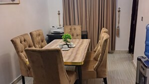 Un coin repas comprenant une table rectangulaire, six chaises rembourrées, une petite plante et un luminaire suspendu au design moderne.