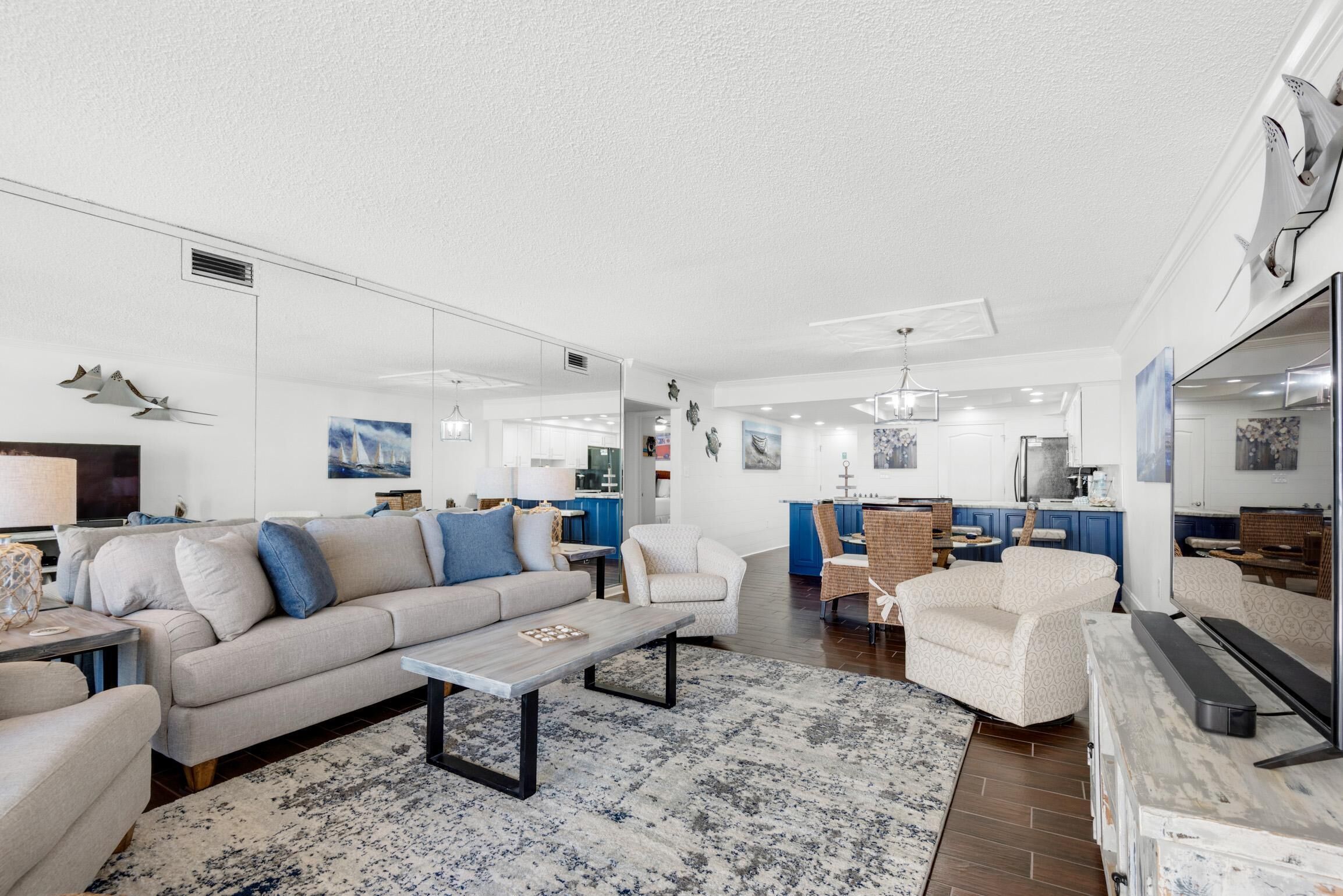 A modern living room with a sofa, armchairs, a coffee table, and a dining area with a table and chairs.