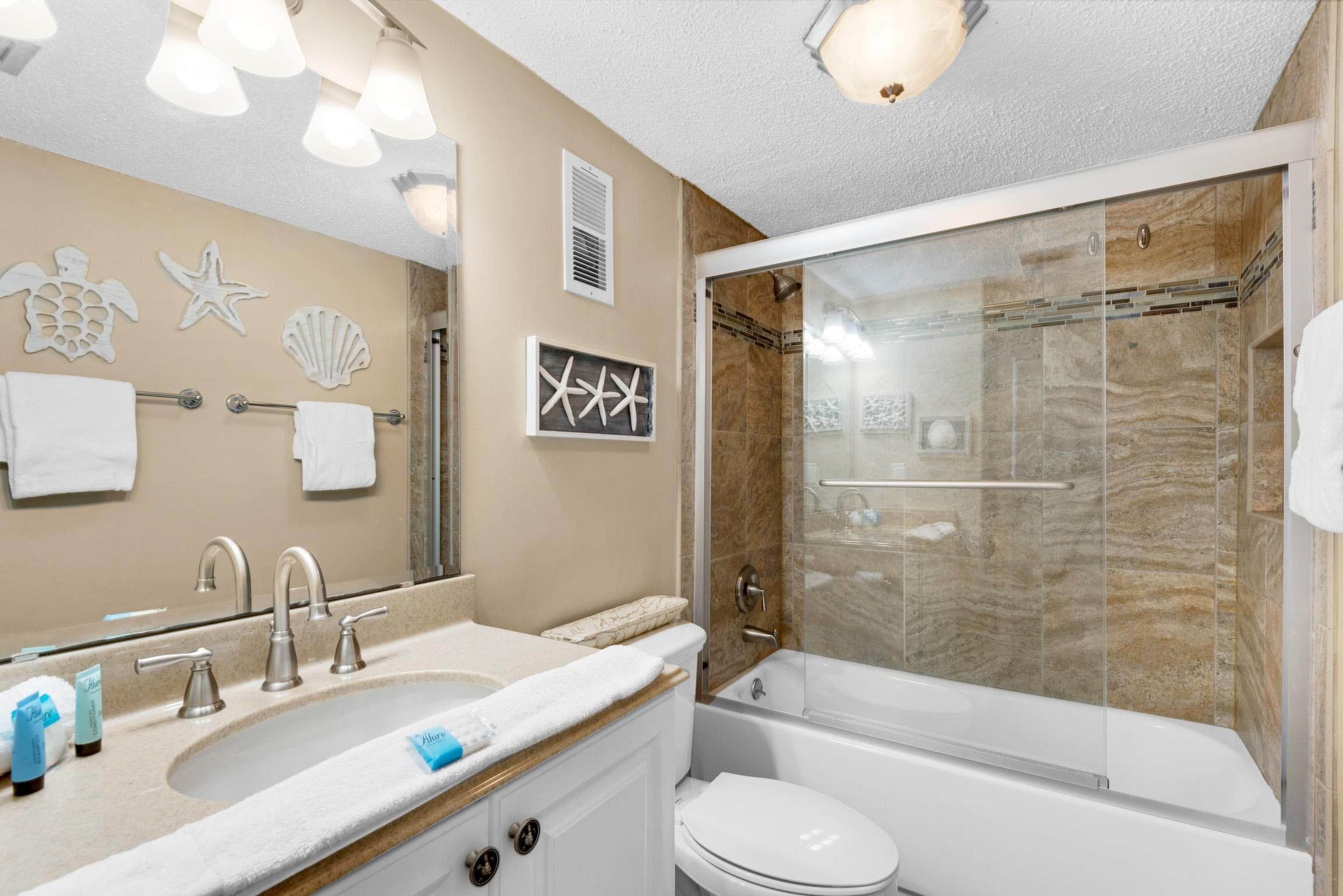 A modern bathroom with a large sink, mirror, and a glass-enclosed shower.