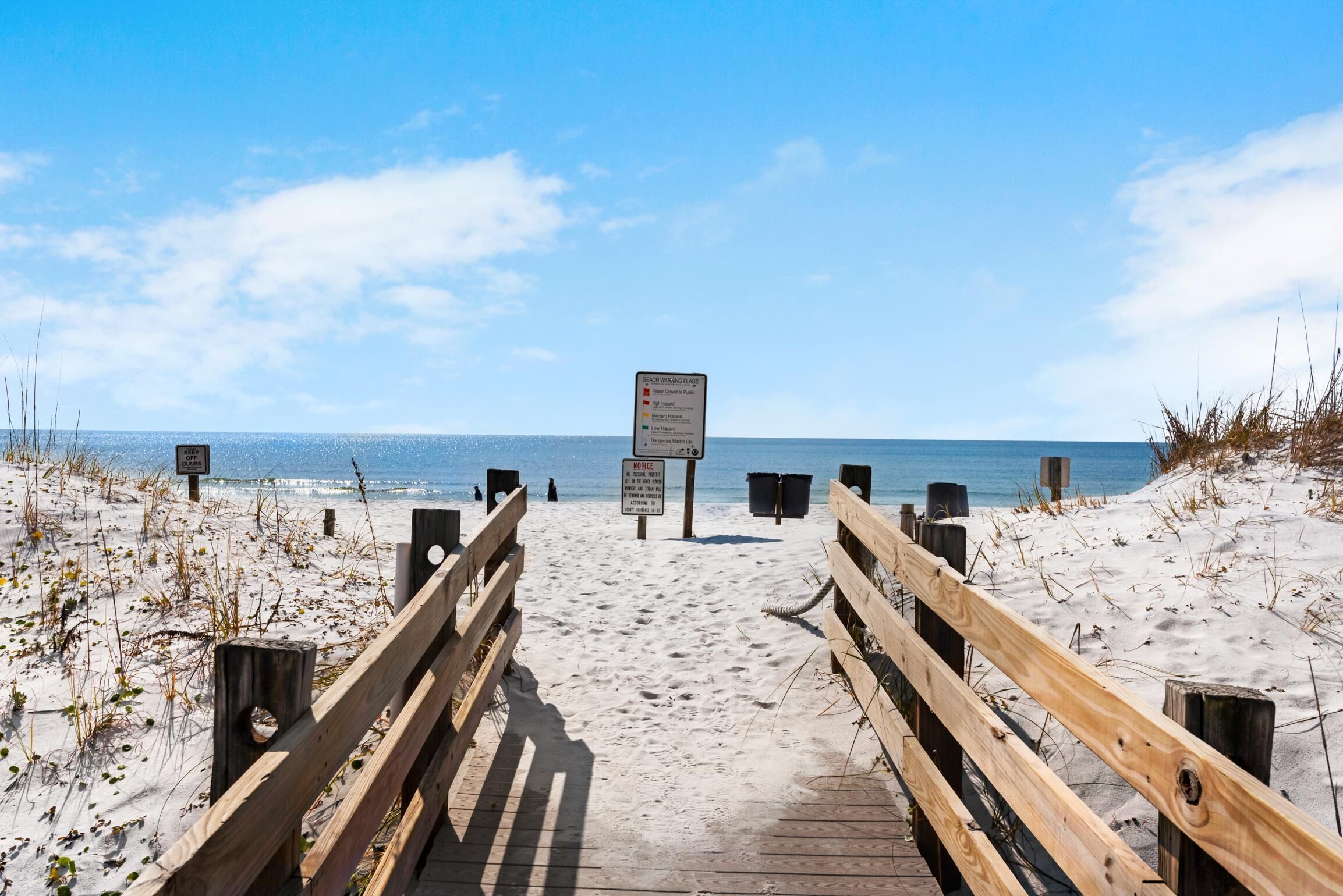 A wooden boardwalk leading to the beach with a clear view of the ocean.