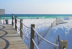 A wooden boardwalk leading to a sandy beach with a rope barrier. - Sea Oats 712 (Fort Walton Beach)