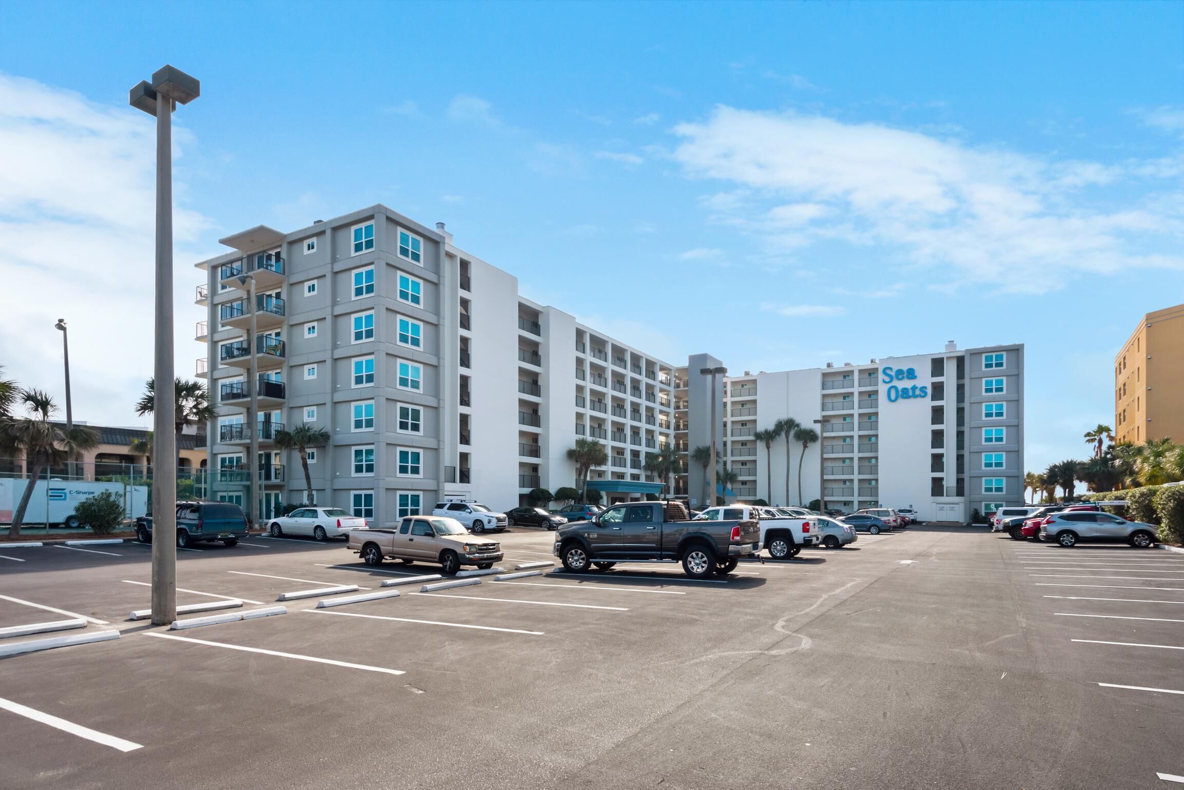 A multi-story hotel with a parking lot in front.