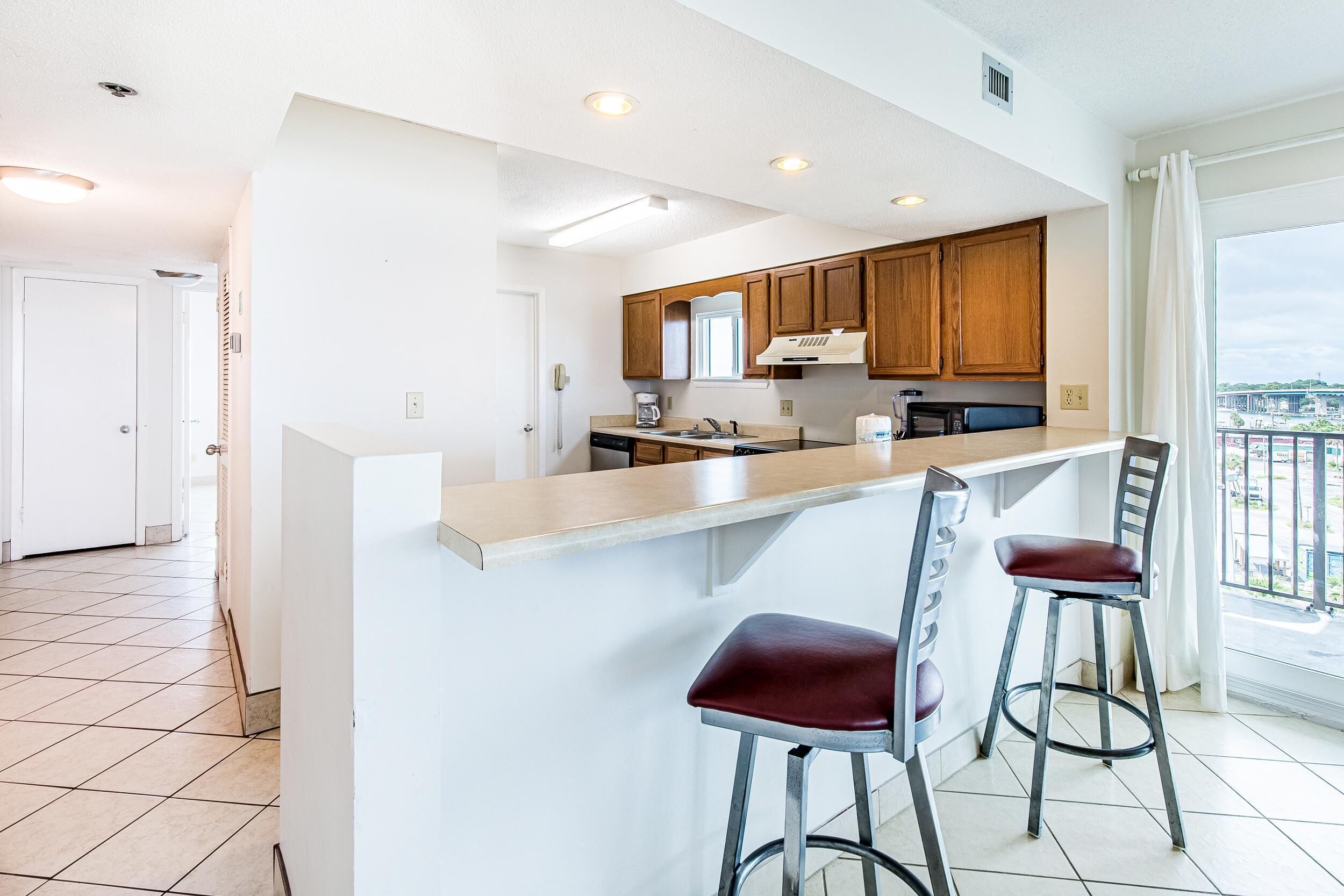 Una cocina moderna con armarios de madera, una isla de acero inoxidable y dos taburetes de bar.