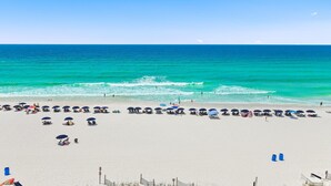 A beach with rows of umbrellas and chairs, a clear sky, and the ocean.
