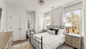 A bedroom with a bed, bedside table, dresser, and a window with curtains. - Grange Getaway at Serenbe (Palmetto)