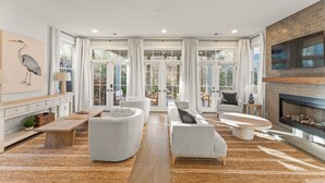 A spacious living room with a fireplace, large windows, and a cozy seating area. - Grange Getaway at Serenbe (Palmetto)