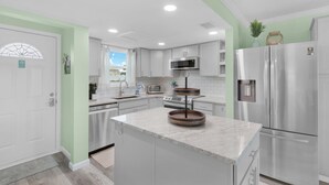 A modern kitchen with white cabinets, stainless steel appliances, and a central island.