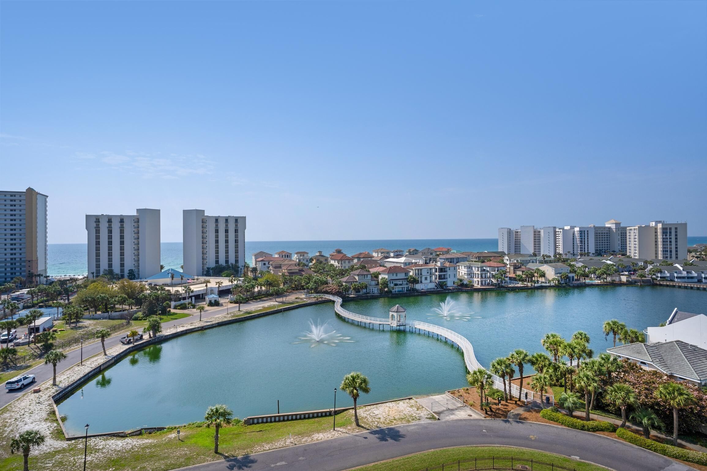 A waterfront property with a curved pool, palm trees, and high-rise buildings in the background.
