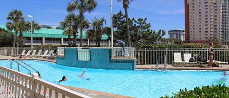 A swimming pool with lounge chairs and palm trees.