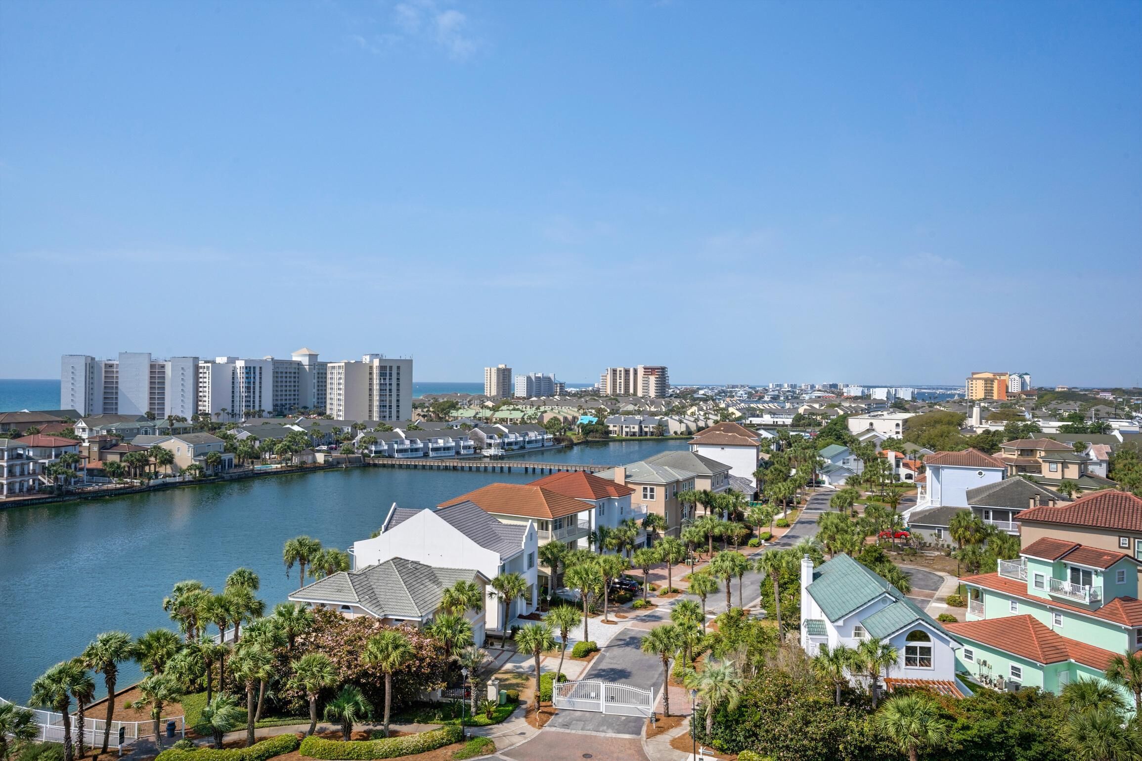 A coastal residential area with a marina, houses with red roofs, and a clear blue sky.