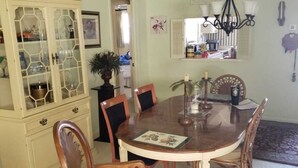 A dining room with a wooden table and chairs, a glass-fronted china cabinet, and a chandelier. - Cozy and beautiful Villa in trendy Fort Myers! Welcome to a home away form home! (Fort Myers)