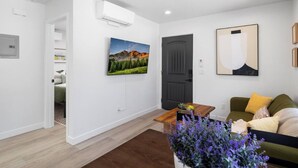 A modern living room with a wooden coffee table, a green sofa, and a painting of a mountain landscape. - Cozy 1bd 1ba Sleeps 3 Close to Disney (Garden Grove)