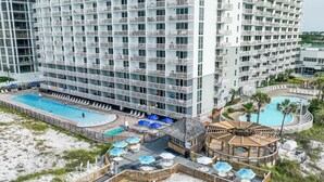 Un hôtel de grande hauteur doté de nombreux balcons, d’une piscine centrale et d’un espace piscine séparé.