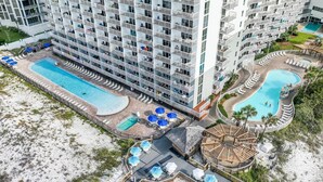 Un hôtel de grande hauteur doté de nombreux balcons, d’une piscine centrale et d’un espace piscine séparé.