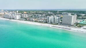 An aerial view of a coastal area with a beach, high-rise buildings, and a marina. - Pelican Beach Resort 213 (Destin)
