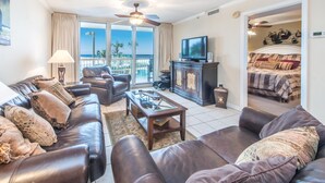 A living room with leather sofas, a television, and a balcony with a view. - Pelican Beach Resort 213 (Destin)