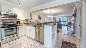 A modern kitchen with white cabinets, stainless steel appliances, and a large island. - Pelican Beach Resort 213 (Destin)