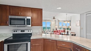A kitchen with wooden cabinets, a stainless steel microwave, and an oven.