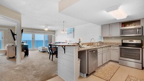 A modern kitchen with stainless steel appliances, a large island, and a dining area with a view. - Islander Beach Resort 6012 (Fort Walton Beach)