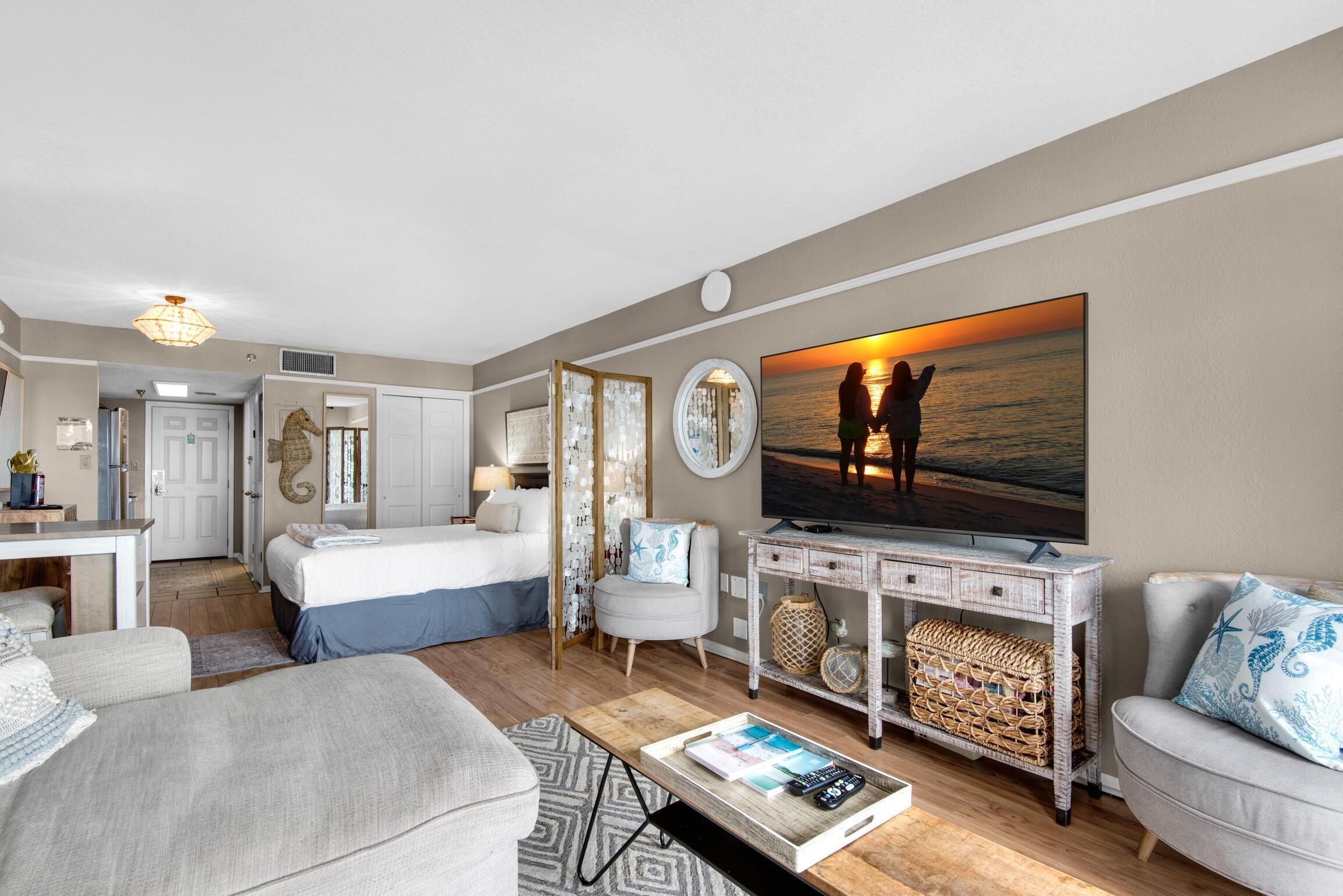 A modern living room with a large TV, a sofa, a coffee table, and a bed.