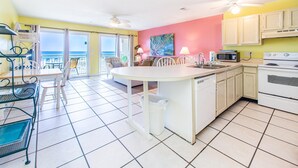 A kitchen with a central island, white cabinets, and a view to the outside.
