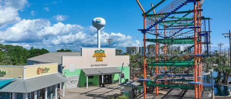 An outdoor amusement park area with a water tower, a play structure, and a building with a sign that reads "Adventure Zone."