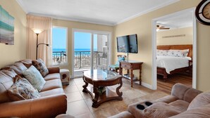 A spacious living room with a leather sofa, a glass coffee table, and a view of the ocean through large sliding doors. - Island Echos #2E (Fort Walton Beach)