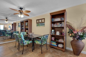 A dining area with a table and chairs, a bookshelf, and a decorative vase.