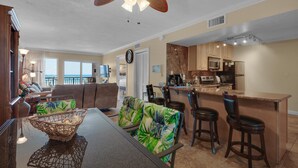 A spacious living area with a dining table, chairs, and a kitchen area with a bar. - Island Echos #2E (Fort Walton Beach)