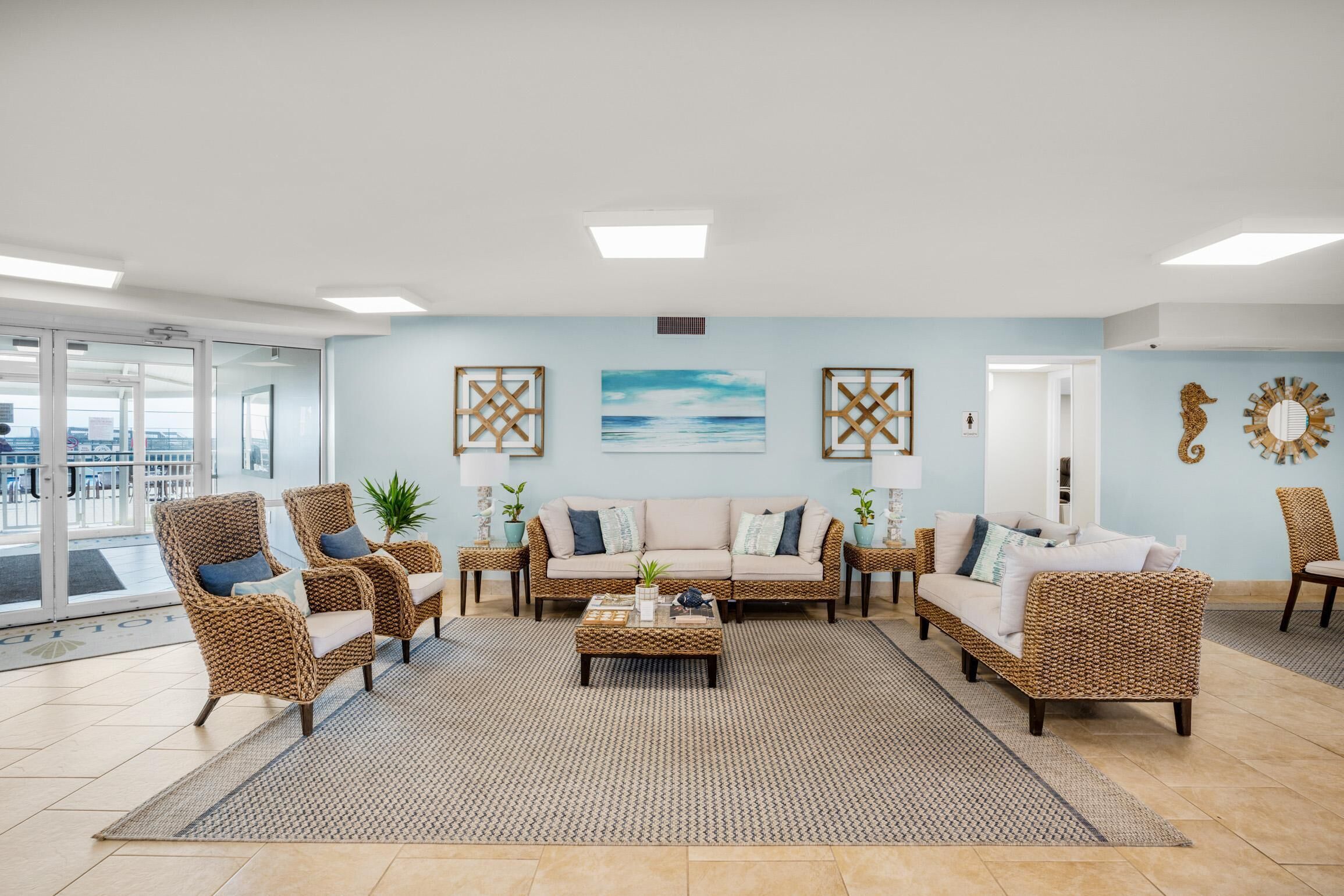 A spacious living area with wicker furniture, a large window, and a view of the city.