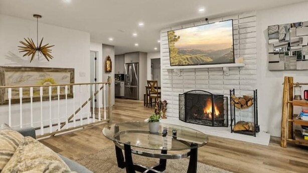 Una sala de estar moderna con chimenea, una mesa de centro de vidrio y una escalera que sube a otro nivel.