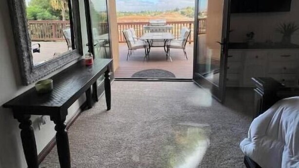 A hotel room with a large sliding glass door leading to a balcony with a table and chairs. - Meadowview Suite (Temecula)