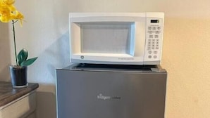 A compact refrigerator with a built-in microwave on top, placed in a kitchen area. - Meadowview Suite (Temecula)