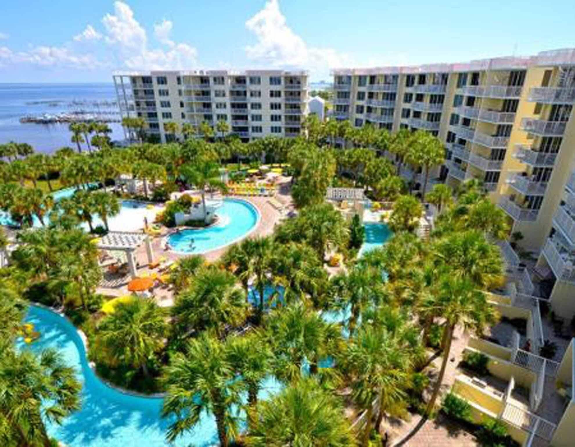 A resort with multiple swimming pools, palm trees, and beachfront views.