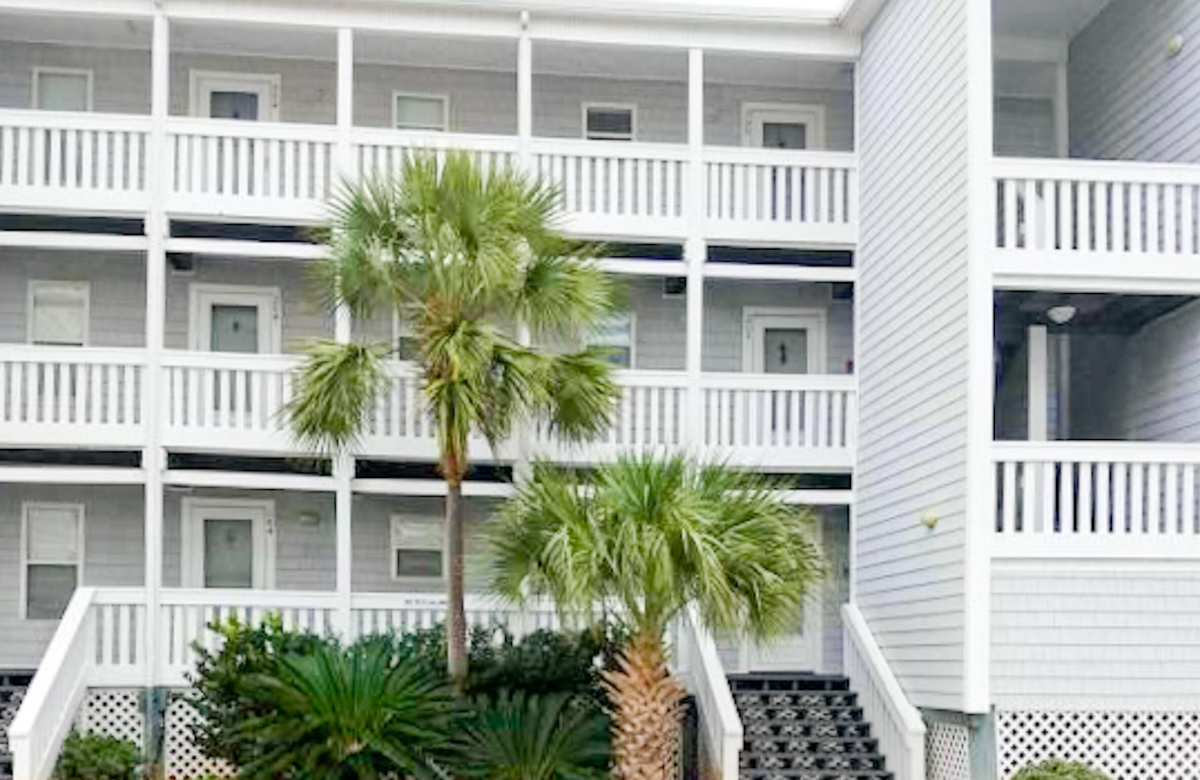 A multi-story hotel with white balconies and a central staircase.