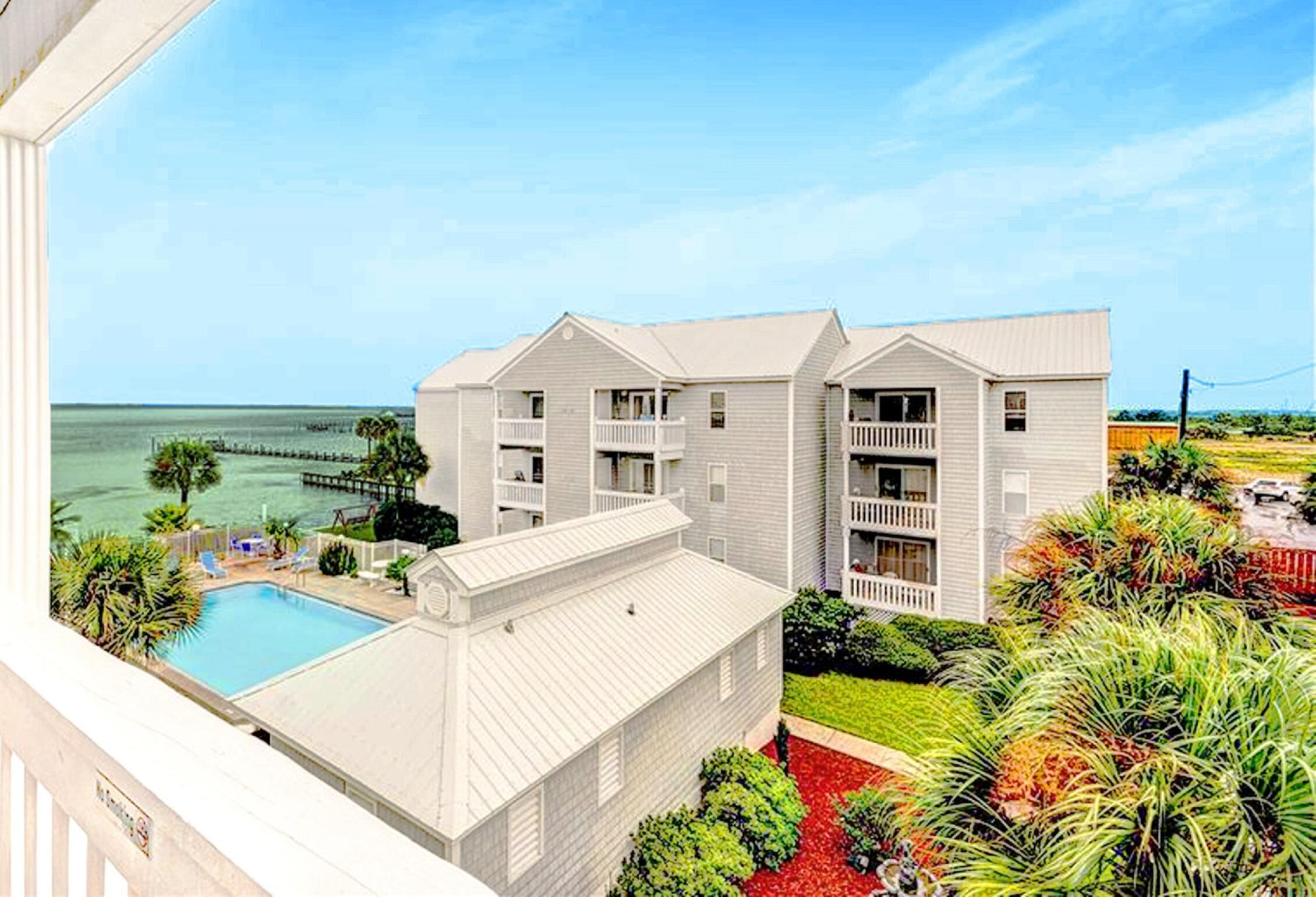 A beachfront hotel with a swimming pool, multiple balconies, and a view of the ocean.