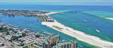An aerial view of a coastal city with a marina, a beach, and a hotel complex.