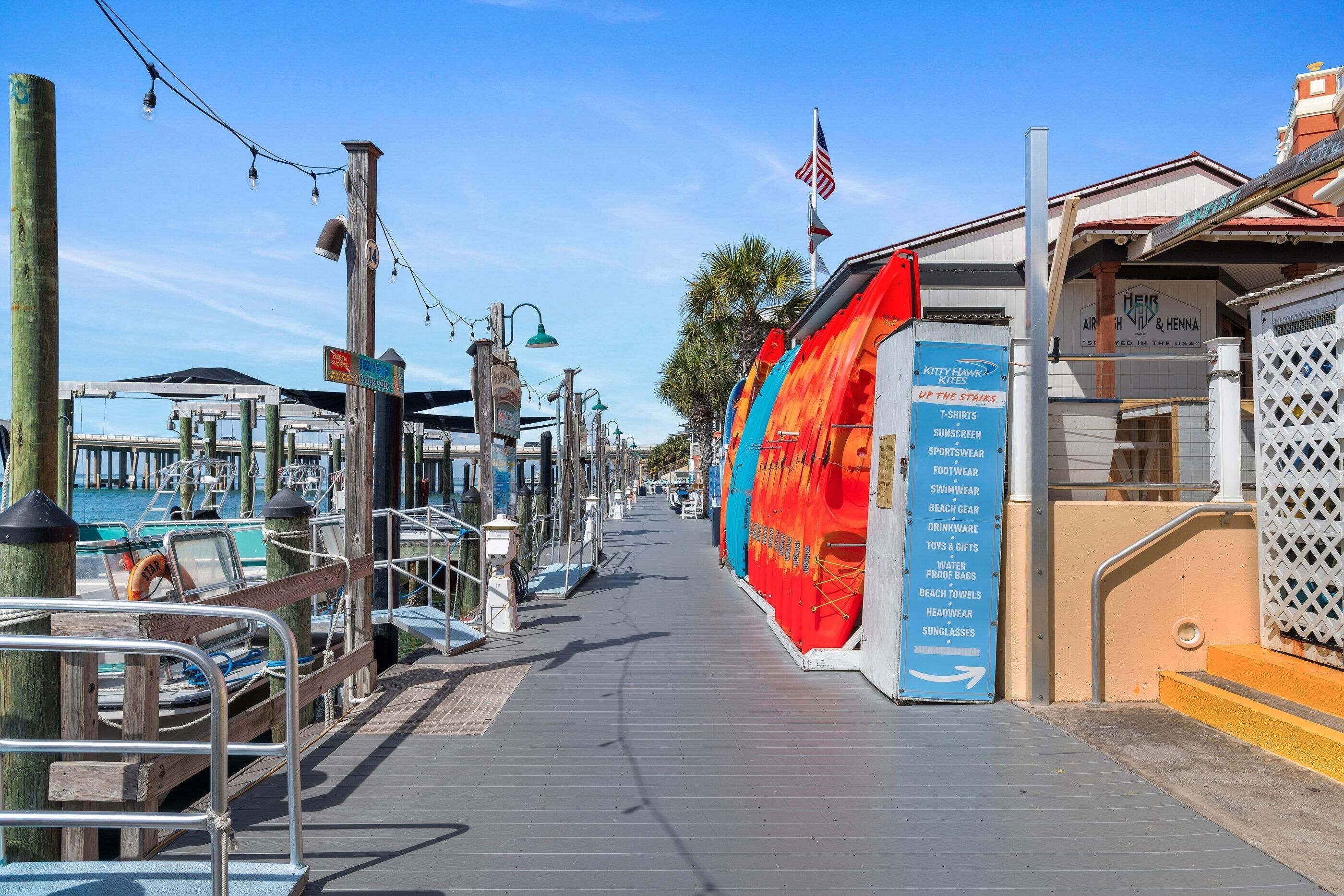 A pier with a wooden walkway, a lifebuoy, and a sign for a store selling t-shirts and sunglasses.
