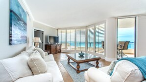 A spacious living room with a large window, a sofa set, a coffee table, and a television. - East Pass 605 (Destin)