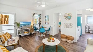 A modern living room with a TV, seating area, and a dining space. - Salt Water Suites - Bright & Cheerful Private Apartment w/ Pool View -  Sunny Days Suite (North Redington Beach)