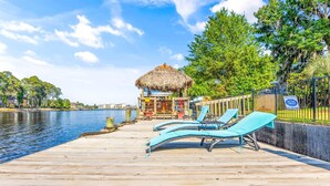 A wooden dock with lounge chairs and a thatched-roof structure. - 3 Level Home on Waterway w/ Heated Pool & Hot tub (Myrtle Beach)