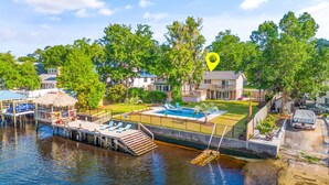 A waterfront property with a swimming pool, dock, and a boat. - 3 Level Home on Waterway w/ Heated Pool & Hot tub (Myrtle Beach)