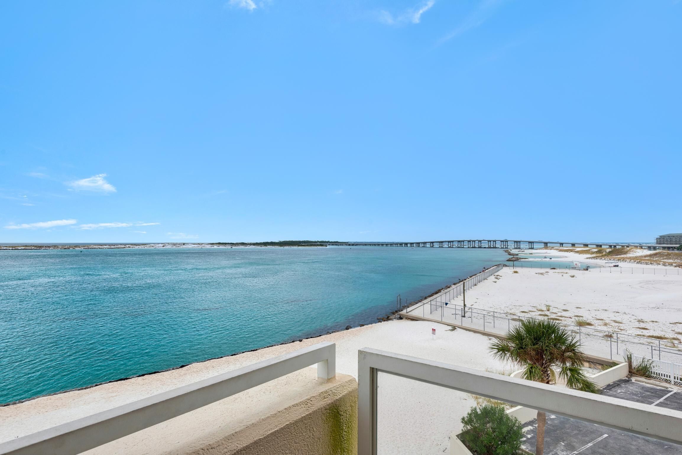 A coastal view with a beach, a pier, and a clear sky.