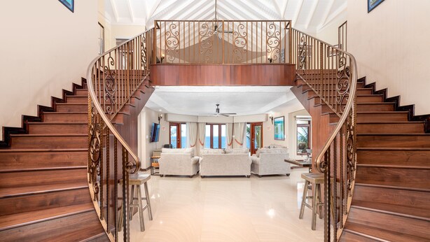 A spacious living area with a wooden staircase leading to an upper level. - Breathaking Luxury Cliffside Villa  (Tower Isle)