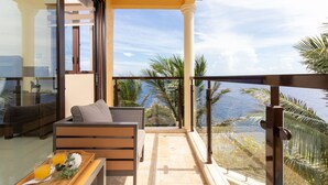 A balcony with a sofa, a tray with drinks, and a view of the ocean. - Breathaking Luxury Cliffside Villa  (Tower Isle)