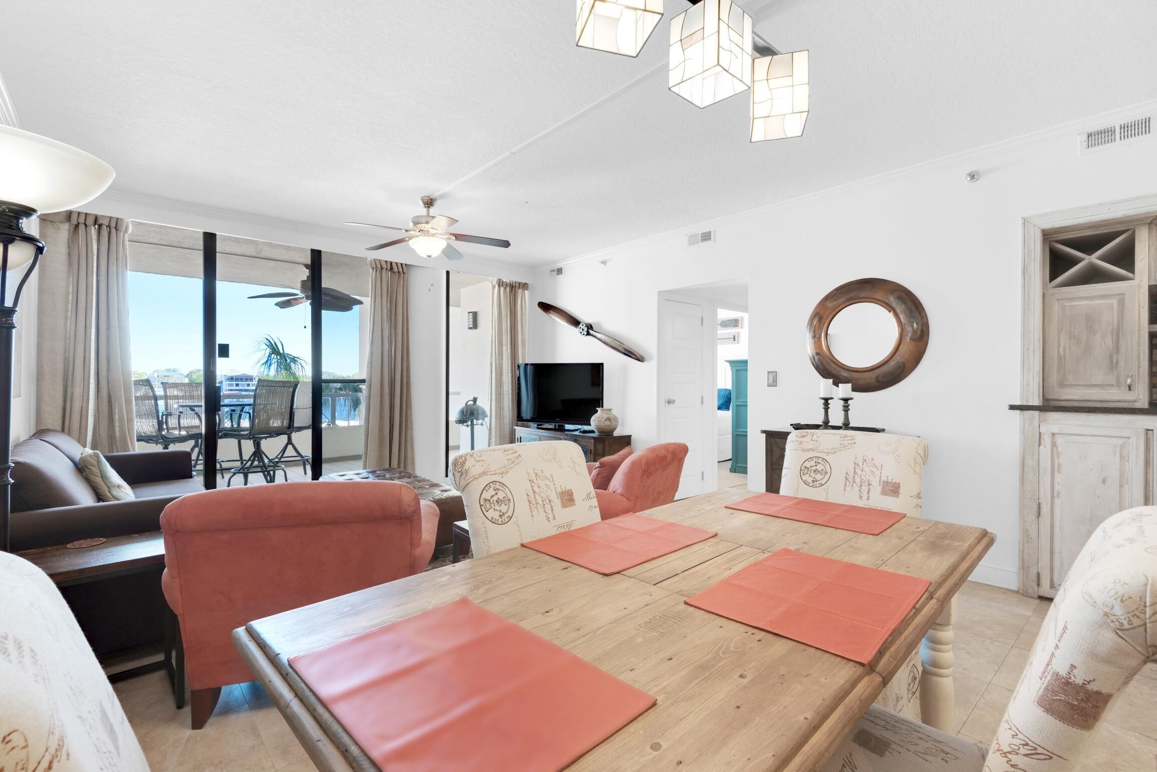 A spacious living area with a wooden dining table, comfortable seating, a television, and a view of the outdoors.