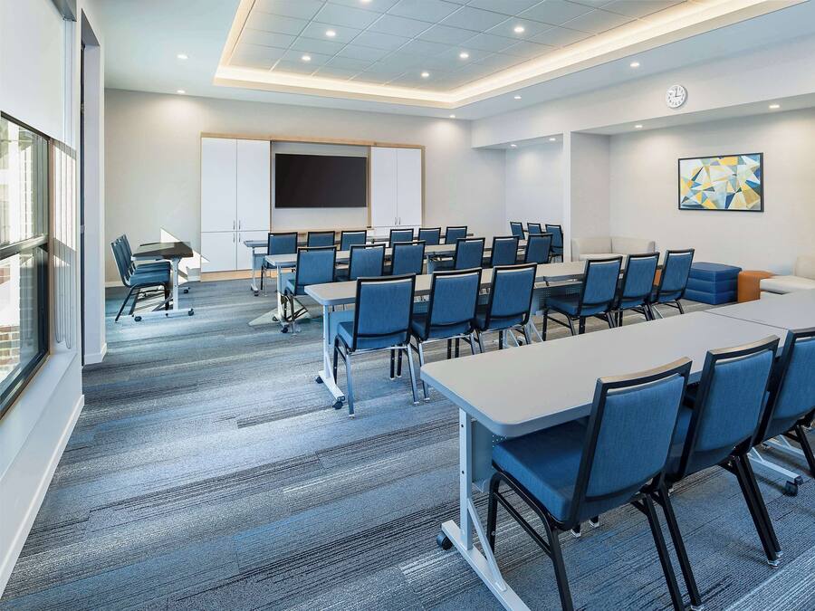 A conference room with multiple tables and chairs, a whiteboard, and a clock on the wall.