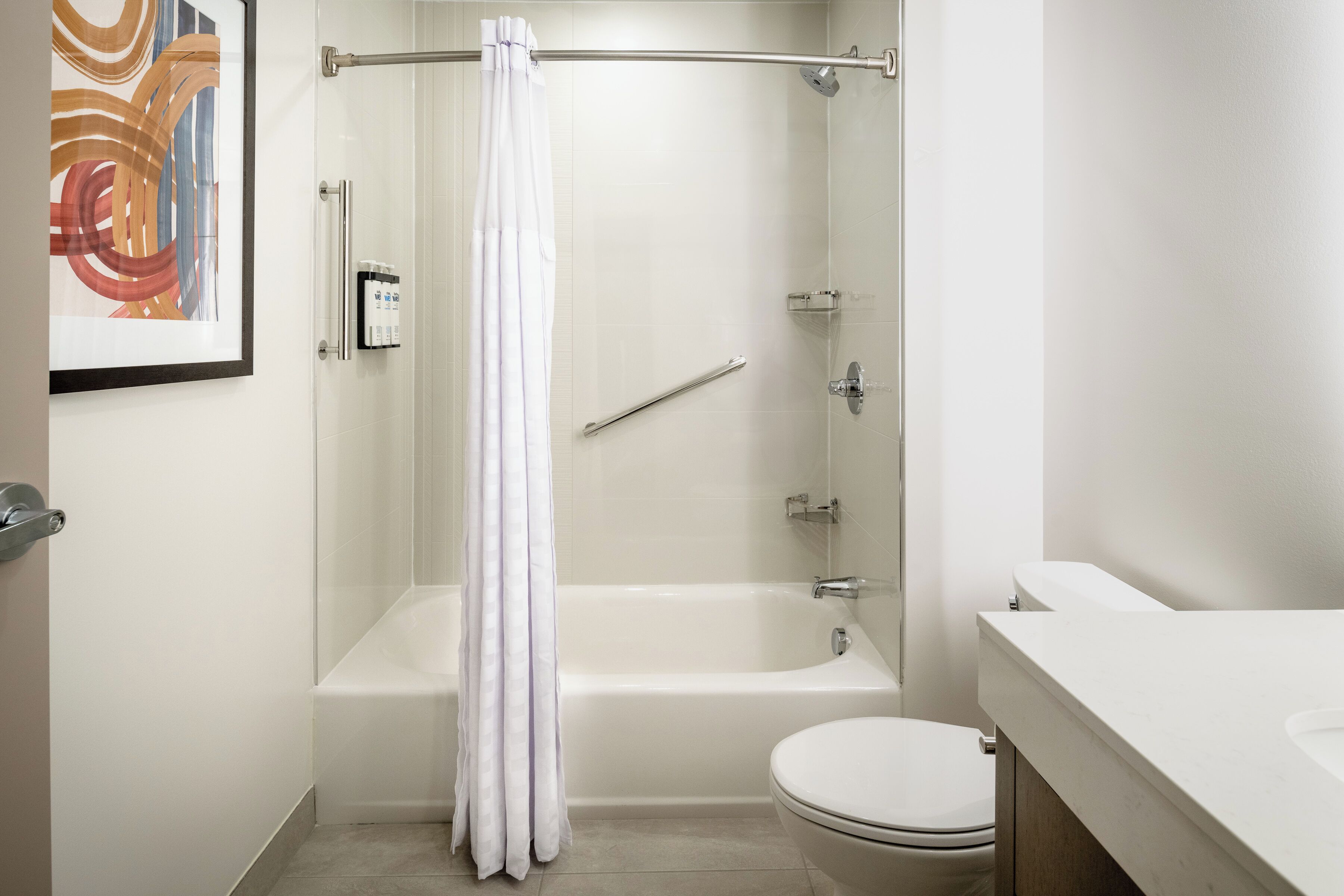 A modern bathroom with a bathtub, toilet, and a shower curtain.